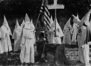 1st November 1922:  Members of American white supremacist secret society the Ku Klux Klan ceremonially initiate a new recruit at a meeting.  (Photo by Topical Press Agency/Getty Images)